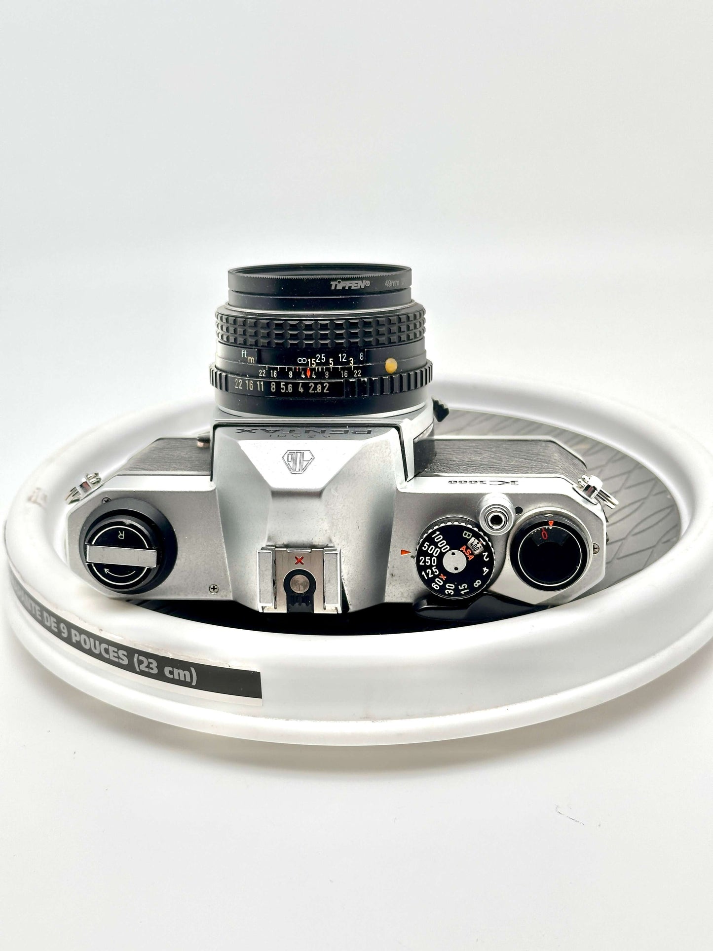 Japanese Asahi Pentax K1000 black 35mm film camera top view with 50mm f2 lens on white background.