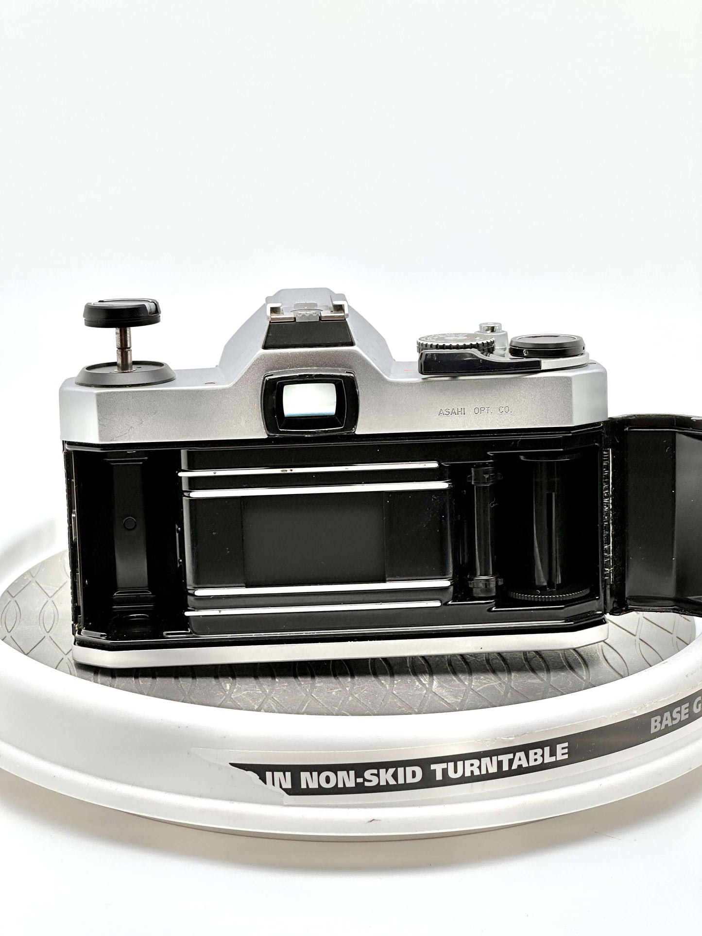 Pentax K1000 film camera rear view showing film compartment and controls on a turntable.