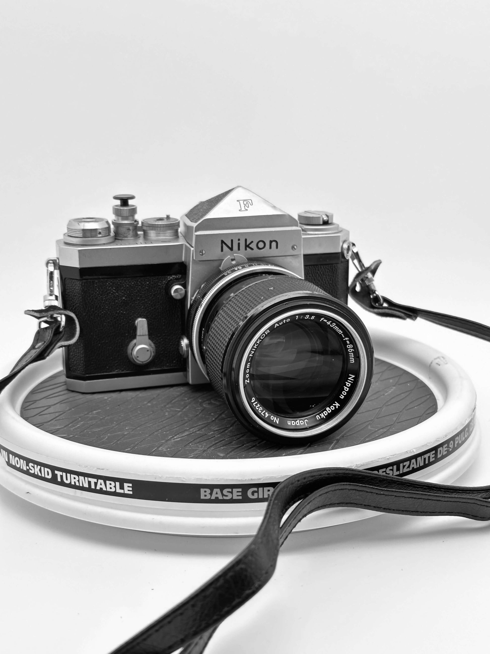 Vintage Nikon F camera with Nikkor 43-86mm lens on a turntable, showcasing classic analog photography.