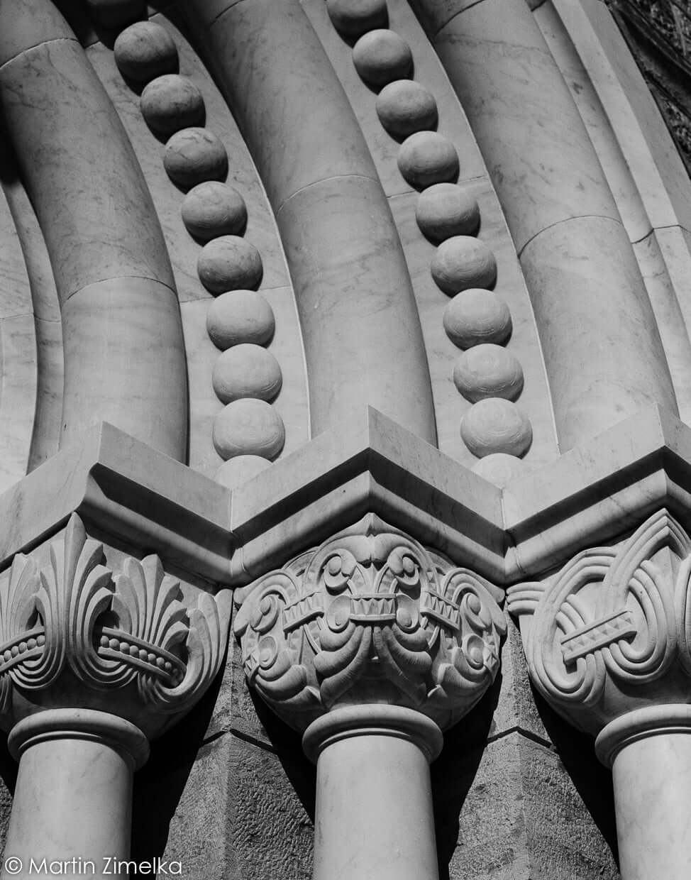 Close-up of decorative stone columns and arches showcasing intricate architectural details in black and white.