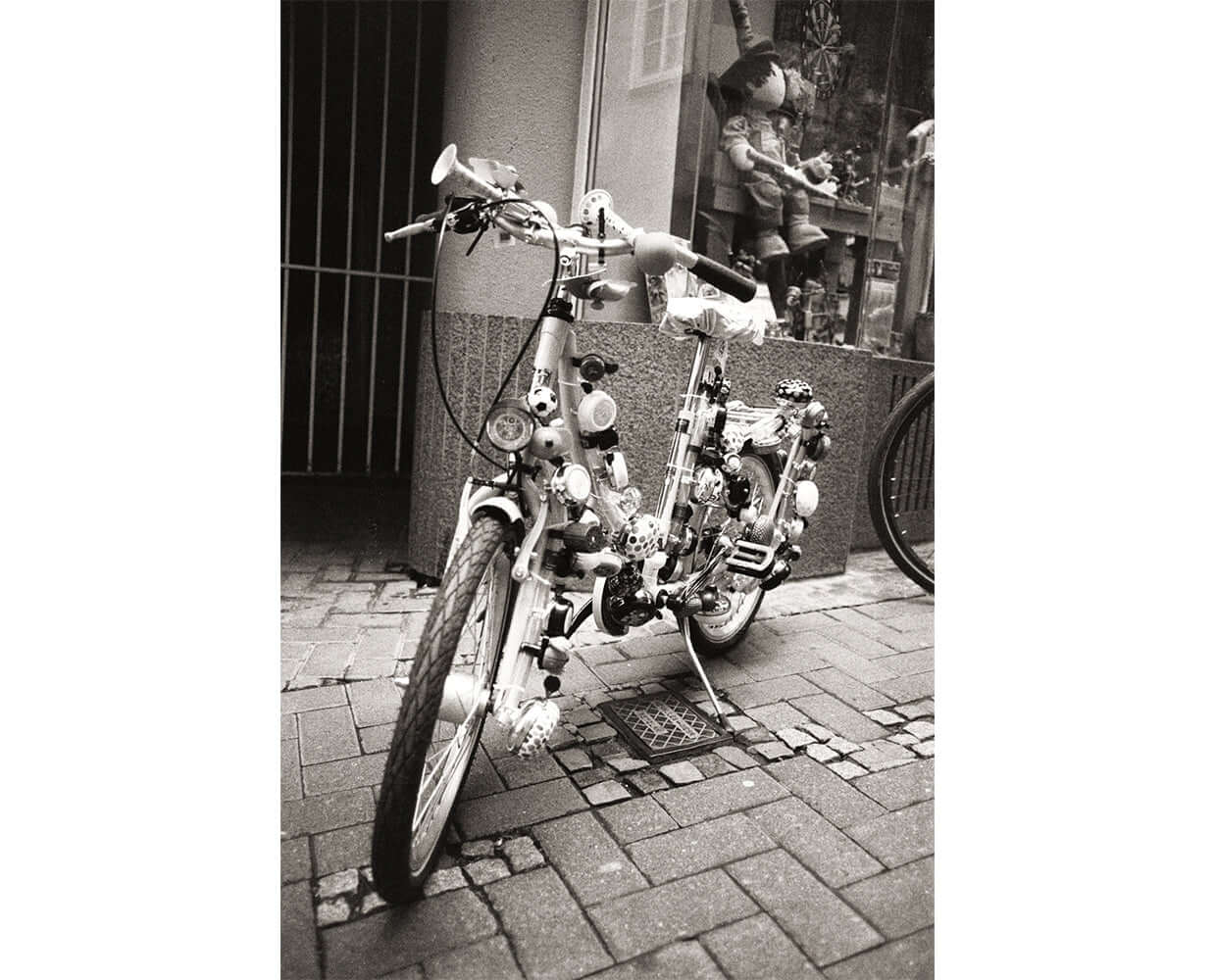 Artistic black and white photograph of a uniquely designed bicycle parked on a cobblestone street.