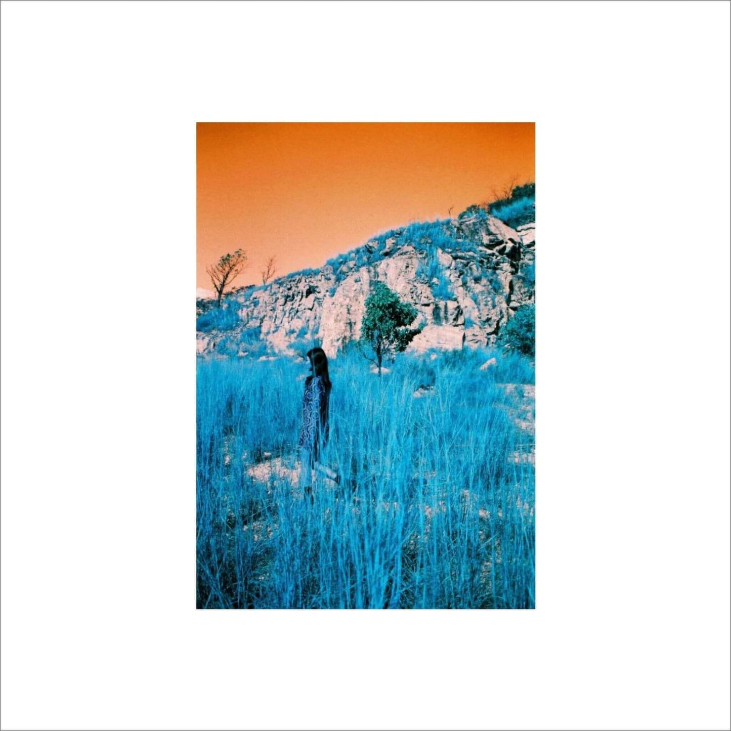 Woman standing in a turquoise landscape with an orange sky, showcasing surreal film effect using Lomography Turquoise film.