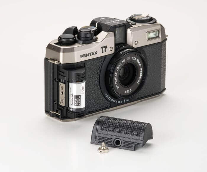 Vintage Pentax 17 film camera with battery compartment open and battery cover removed on white background