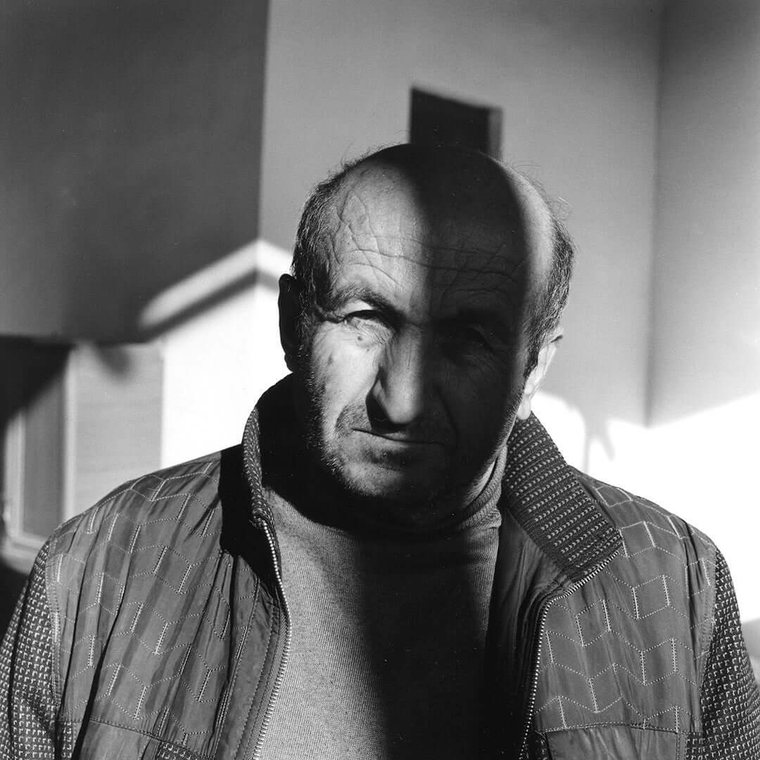 Black and white portrait of an elderly man in dramatic lighting, showcasing the grain and detail of 400 ISO Bergger Pancro film.