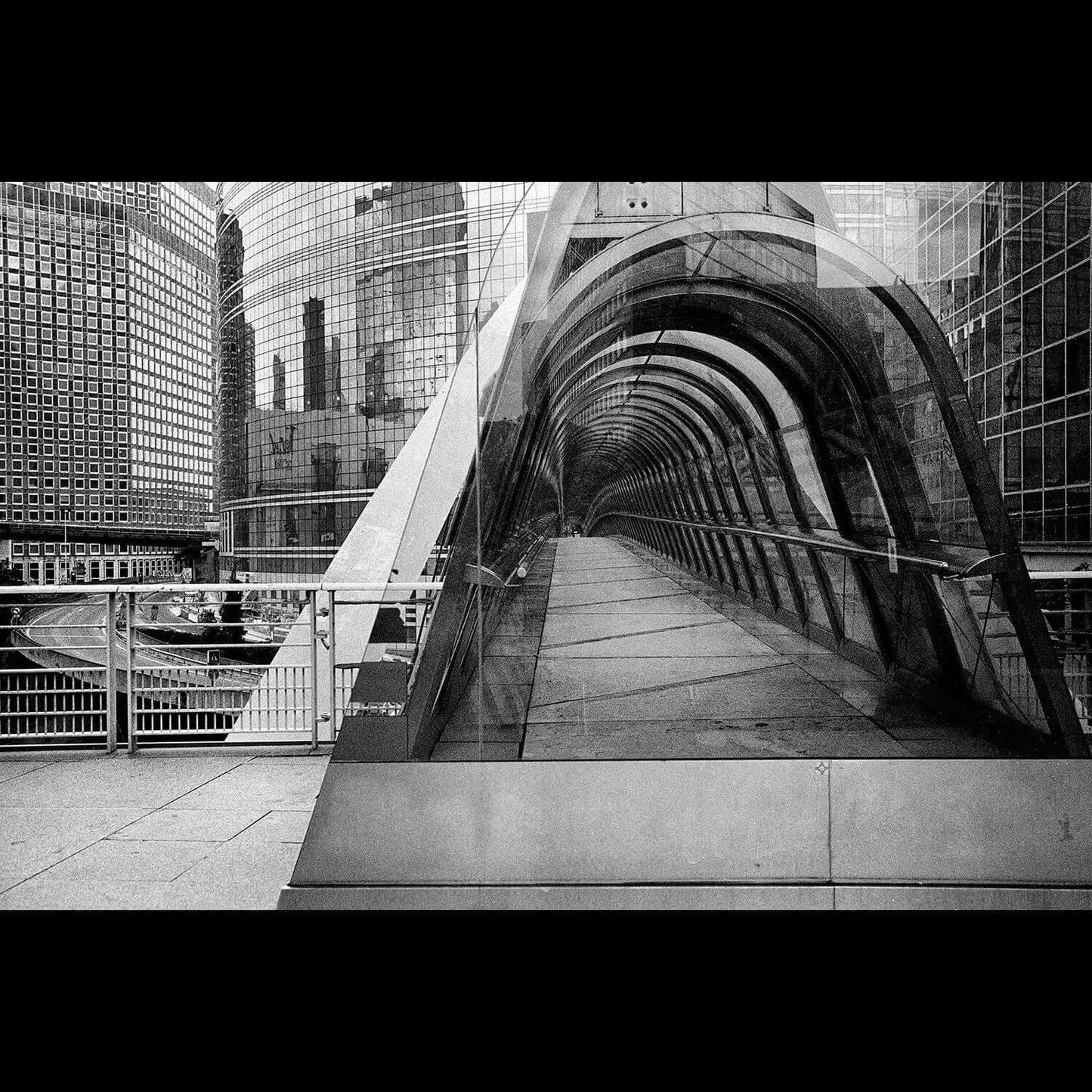 Modern black and white cityscape captured with Bergger Pancro 400 ISO 35mm film showcasing a futuristic glass walkway and skyscrapers