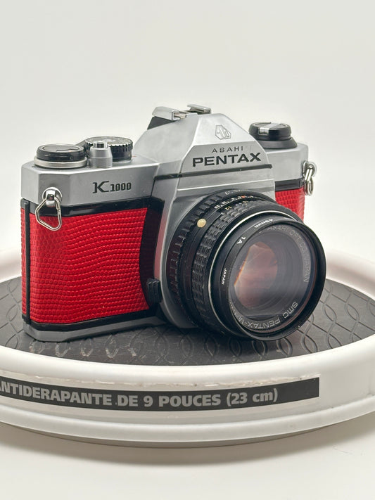 Japanese Asahi Pentax K1000 red used 35mm film camera with 50mm f1.7 lens on display.