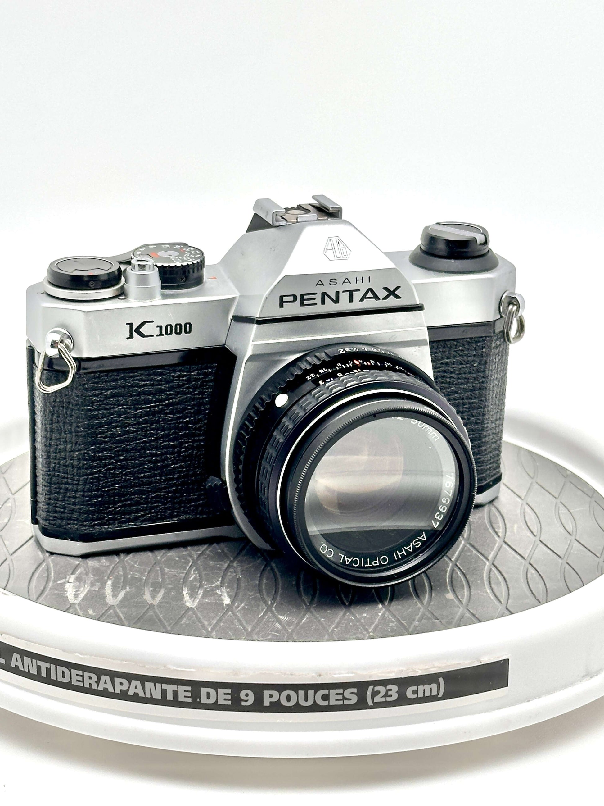 Japanese Asahi Pentax K1000 black 35mm film camera with 50mm f2 lens on display. Classic photography gear.