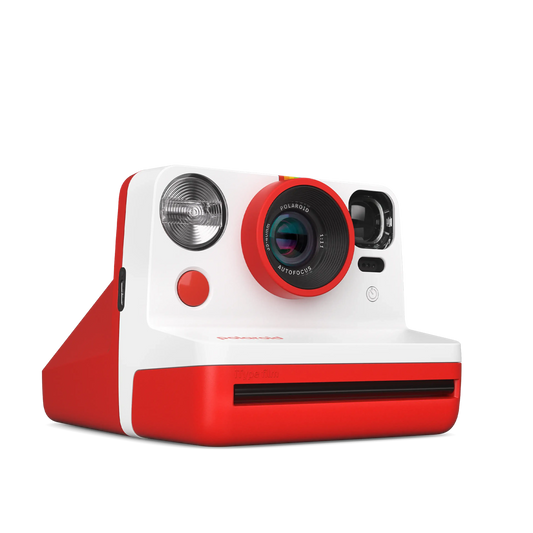 Red and white instant Polaroid camera with lens and flash.