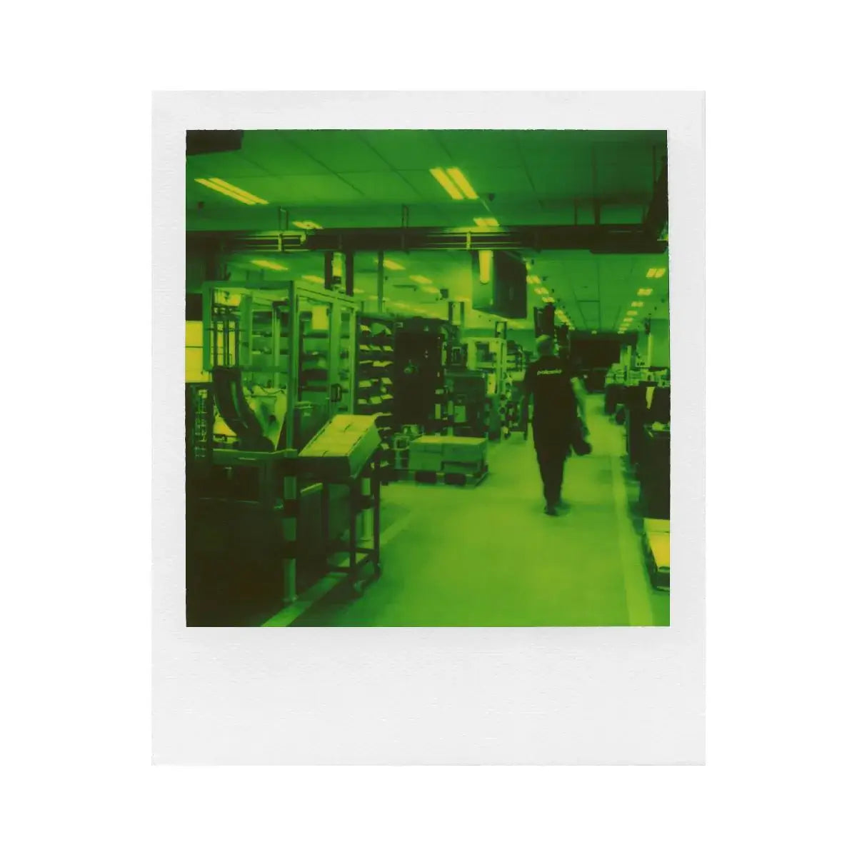 Polaroid Green 600 Instant Film photo of a factory interior with a person walking, captured with a distinctive green hue.