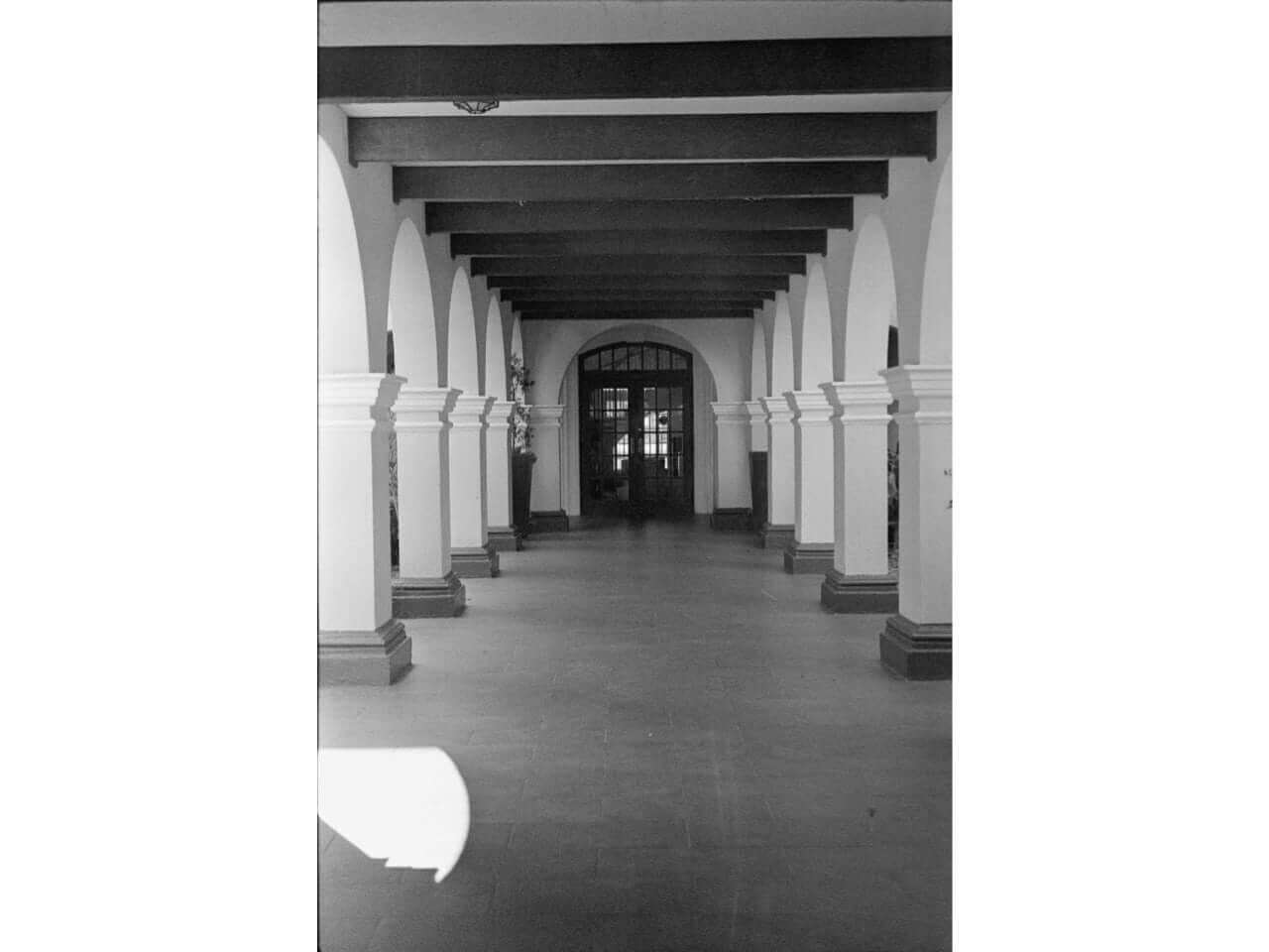 Historical building corridor with arched columns and decorative beams.