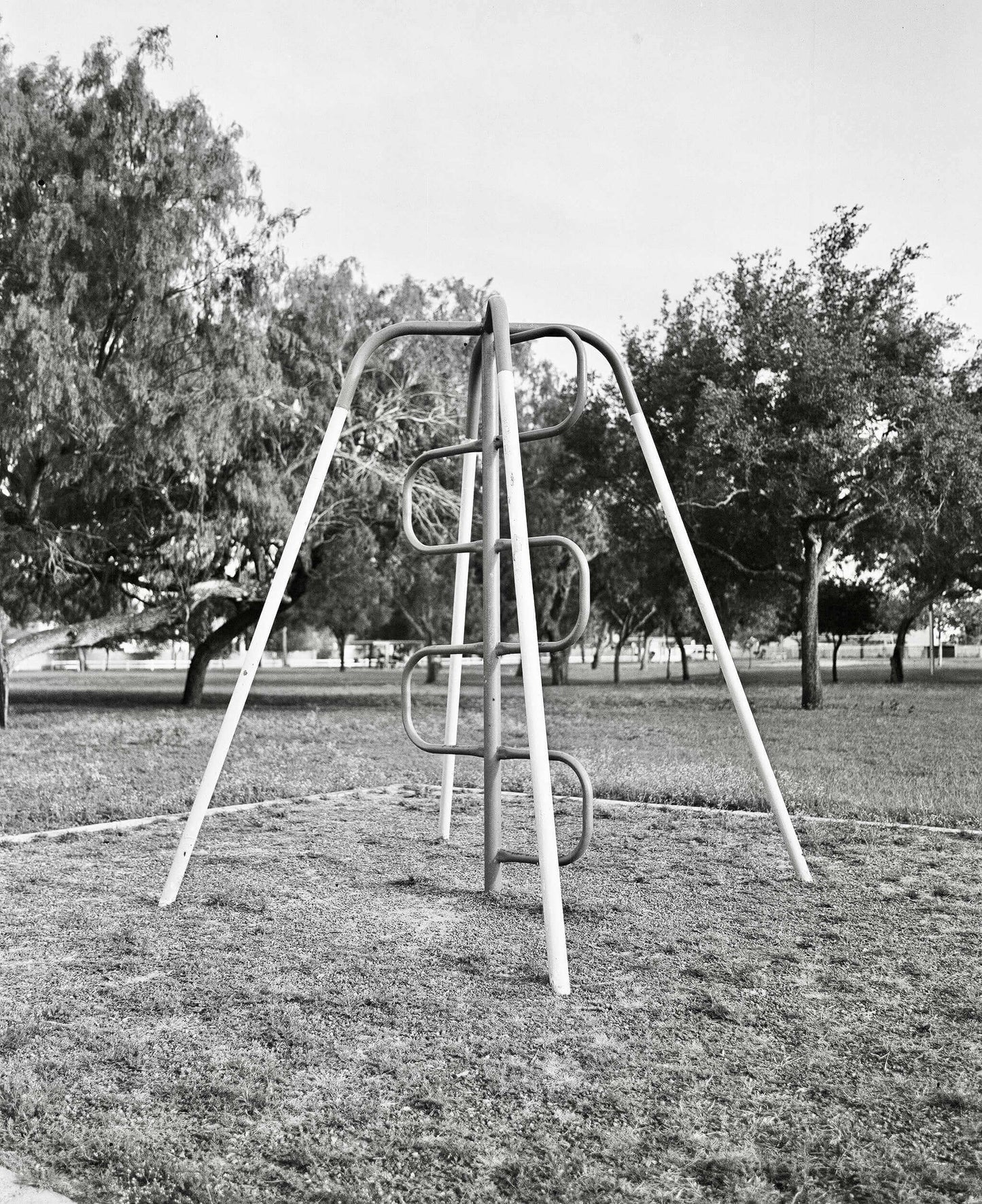 Vintage metal playground climber in a park setting with trees in the background