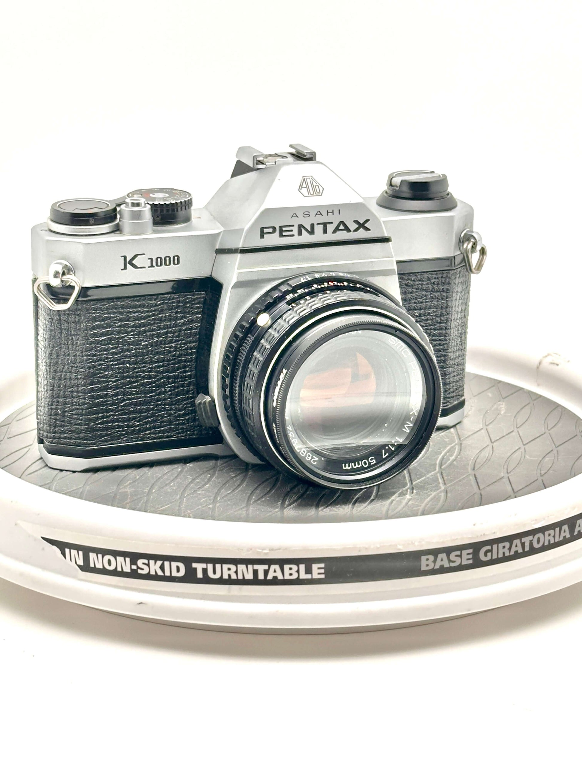 Asahi Pentax K1000 black used 35mm film camera with 50mm f1.7 lens on a turntable.