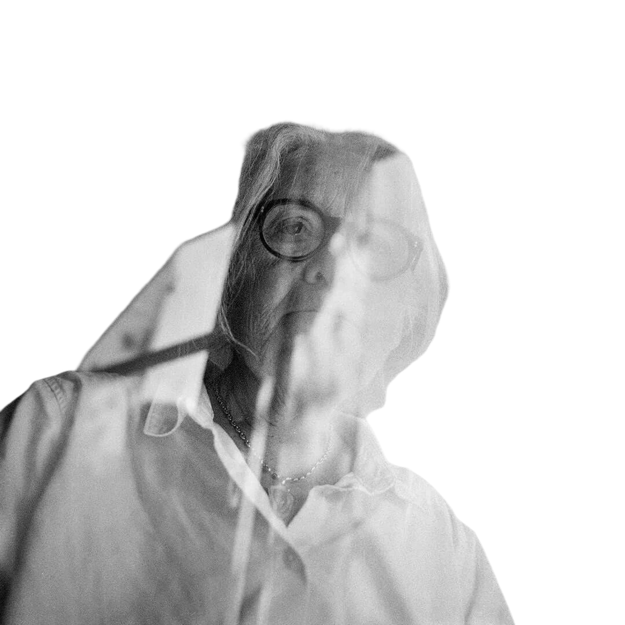 A woman with glasses and light-colored hair, wearing a white collared shirt.