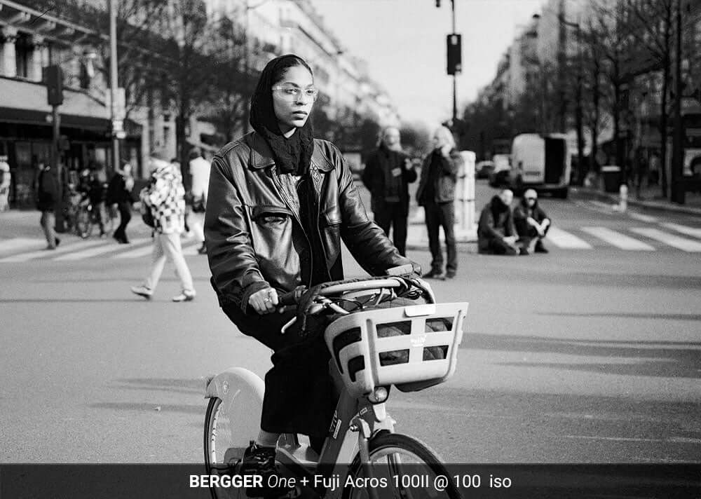 Person biking on a street in black and white, developed with BERGGER ONE and Fuji Acros 100II film at 100 ISO