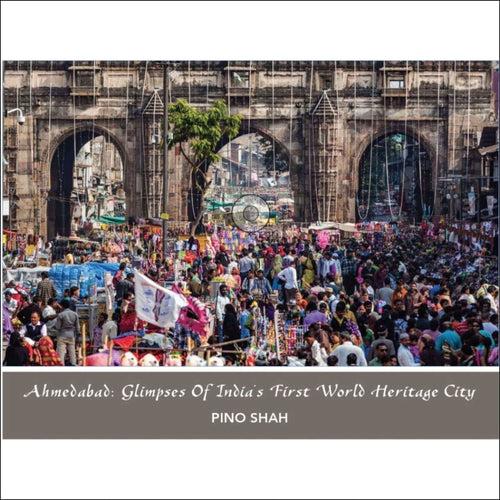 The image displays a vibrant, bustling street scene in ahmedabad under an archway of historic stone architecture.