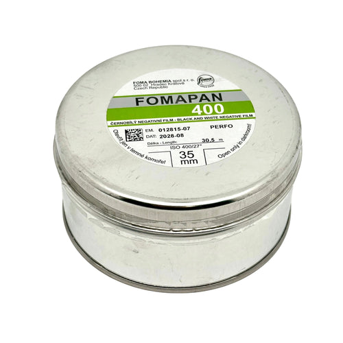 A cylindrical silver metal canister containing fomapan 400 black and white negative film, labeled with green and gray branding.