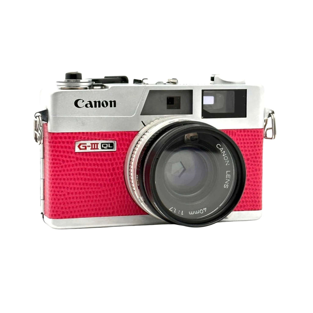 A vibrant pink and silver canon g-iii ql film camera with a textured finish.