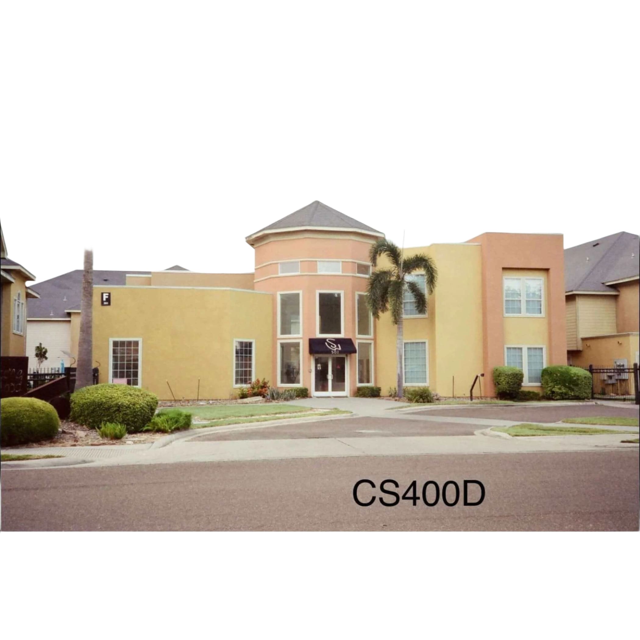 The image shows a two-story building with peach and yellow stucco walls, large windows, and a dark awning over the entrance.