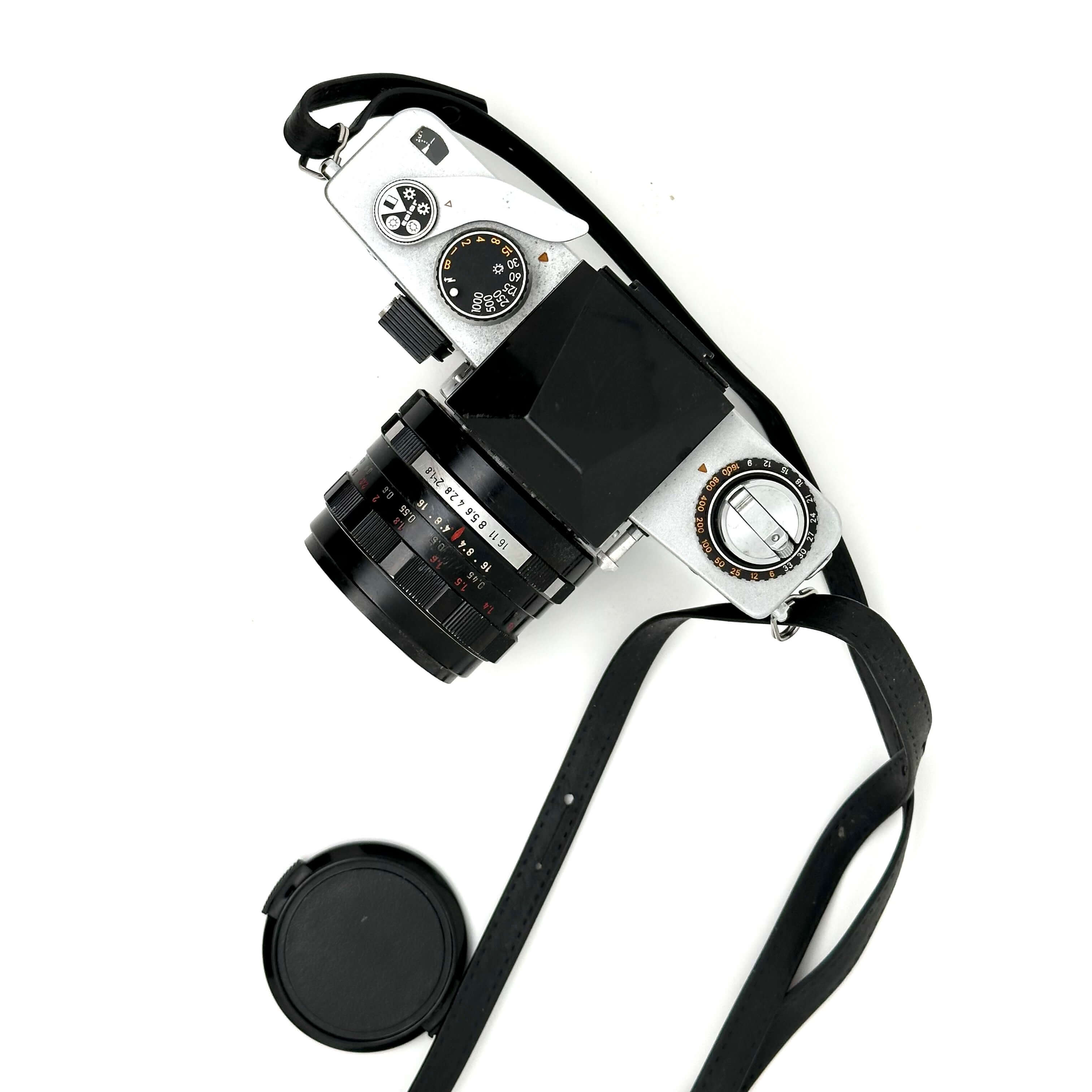 Exakta RTL 1000 vintage 35mm film camera with lens and strap, top view on white background.