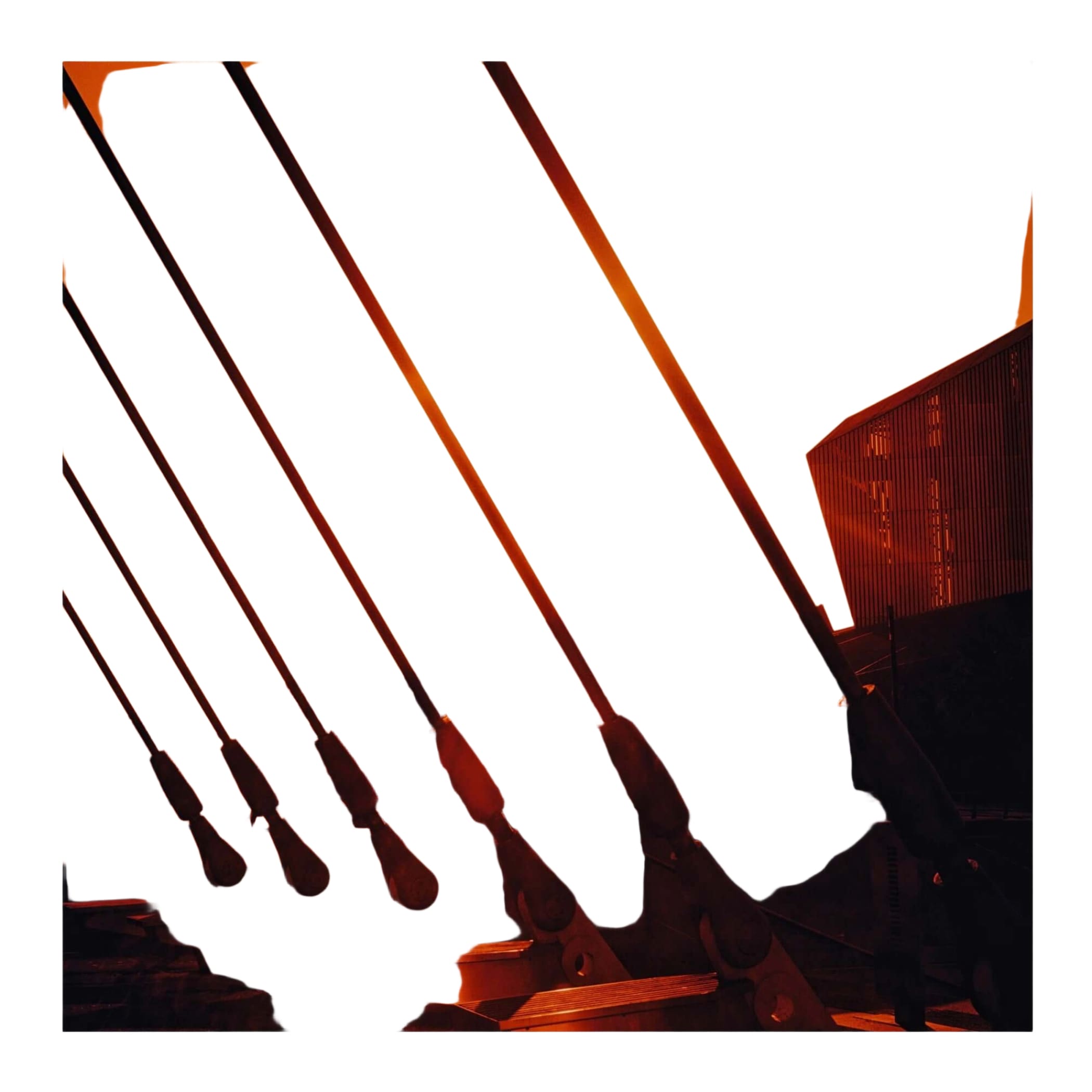 A modern bridge with sleek, dark metal cables stretching diagonally across a warm orange sunset sky.