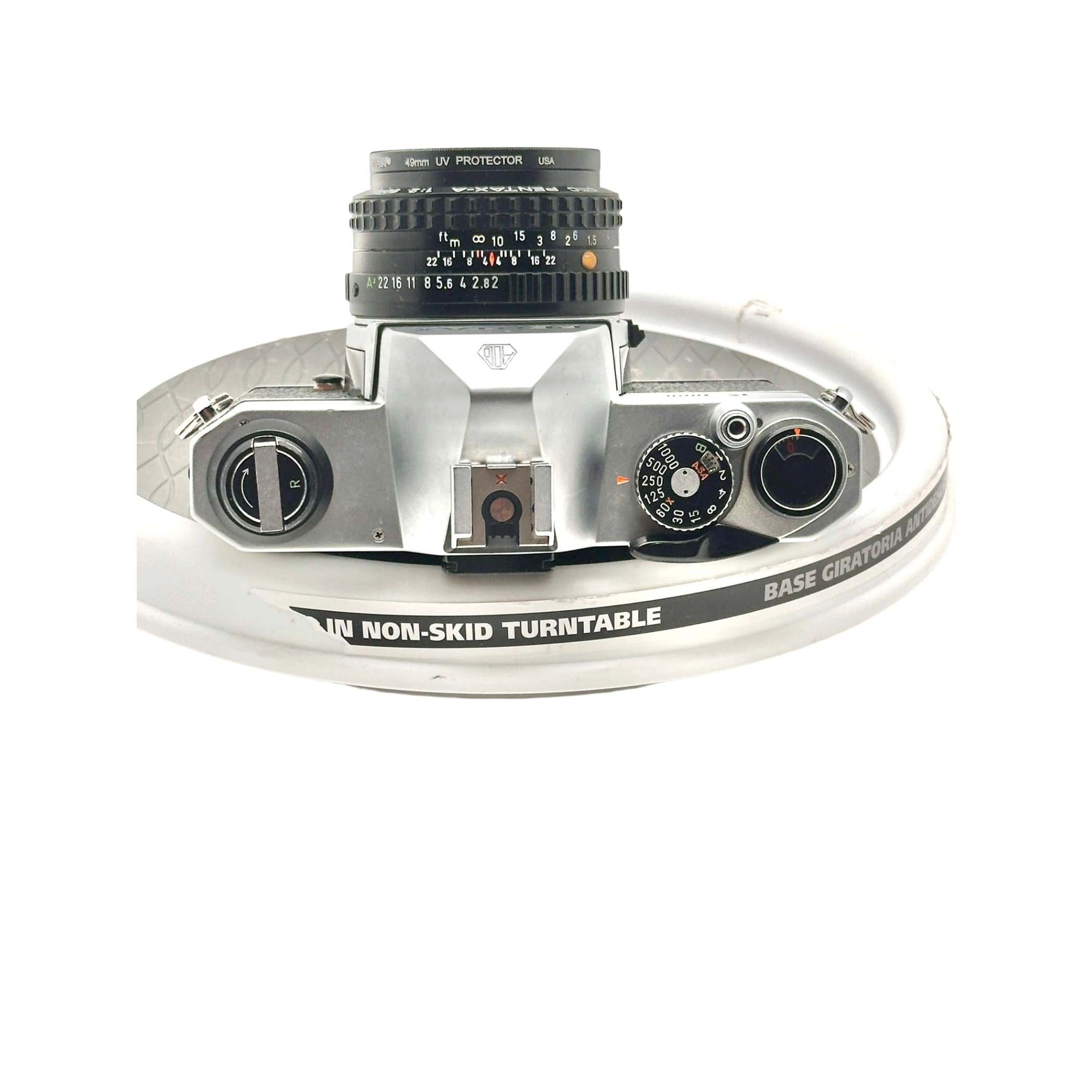 Silver-bodied canon ae-1 film camera with a black 40mm uv protector lens mounted on top.