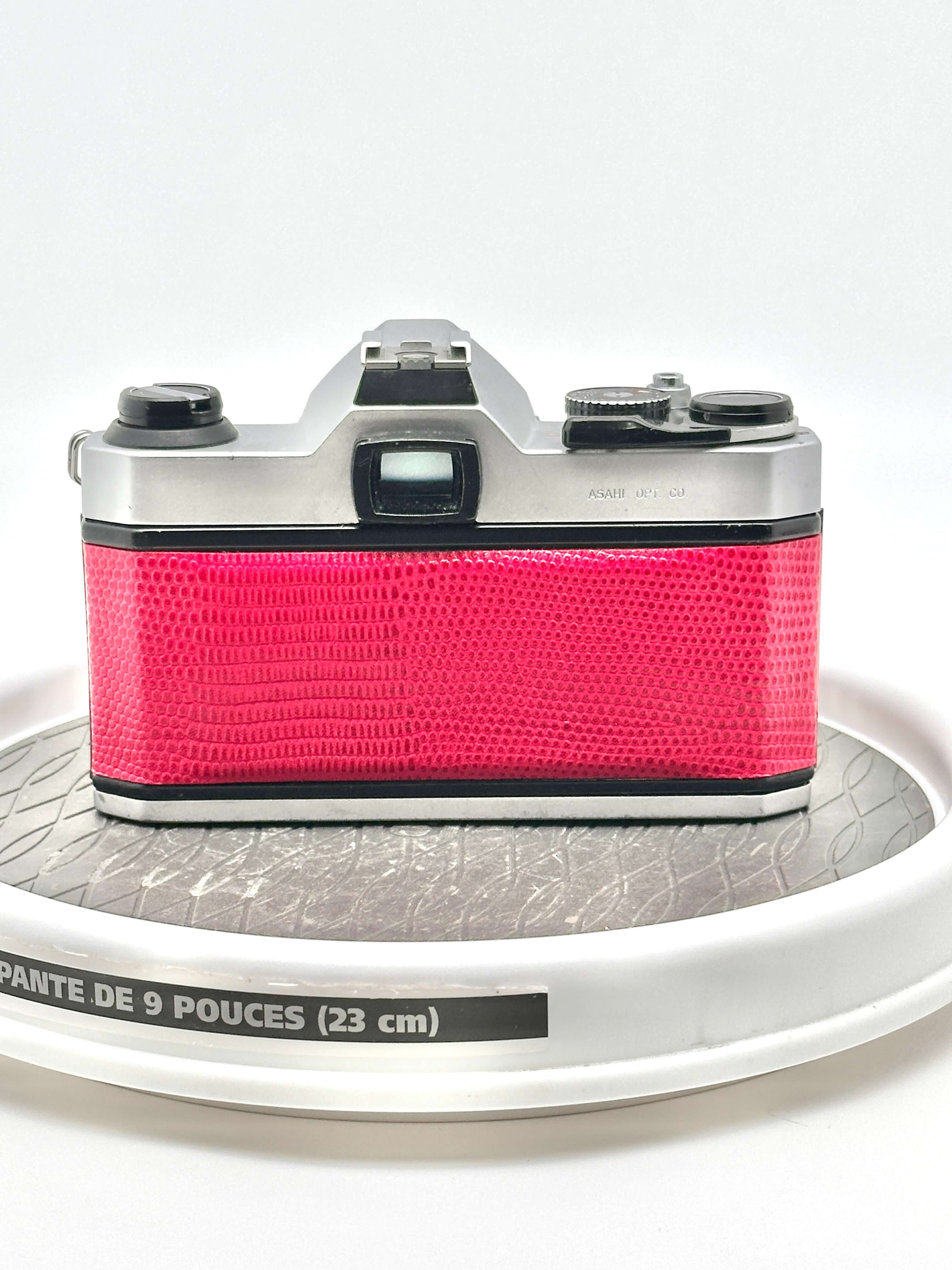 Rear view of a vibrant red Japanese Asahi Pentax K1000 35mm film camera on a display.