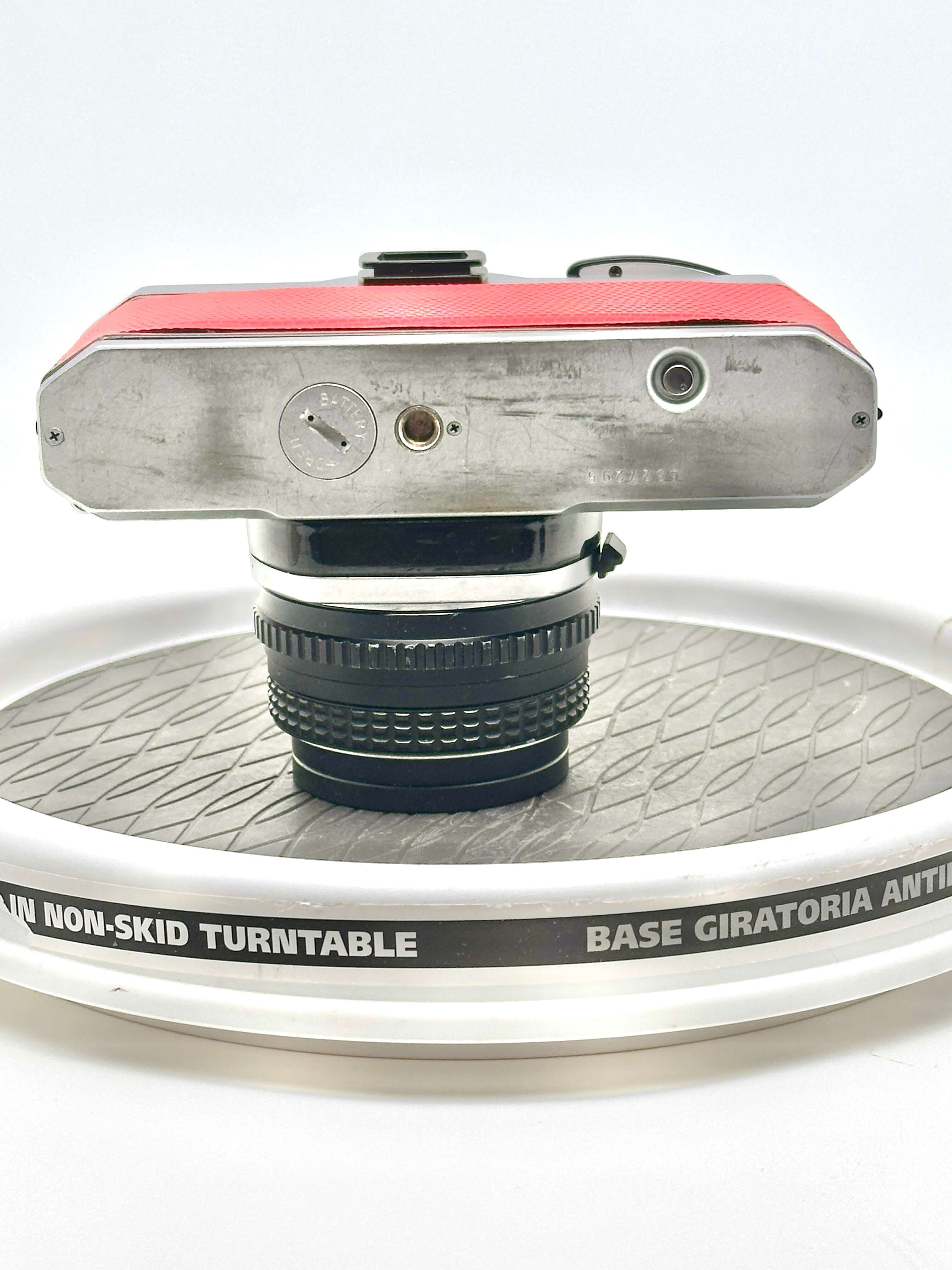 Top view of a red used Pentax K1000 35mm film camera with 50mm f1.7 lens on a non-skid turntable.