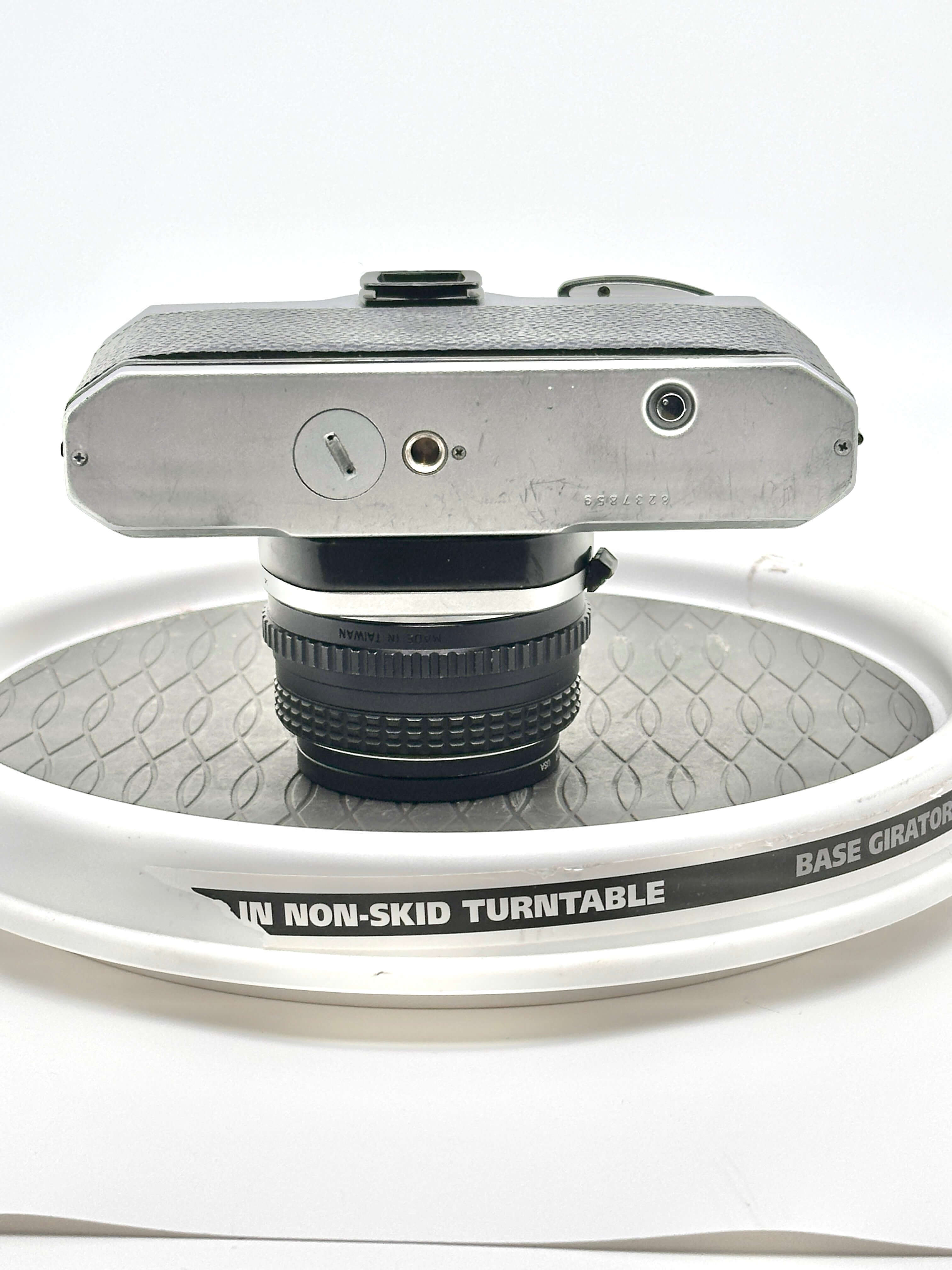 Top view of a Japanese Pentax K1000 camera mounted on a non-skid turntable showcasing its design and lens.