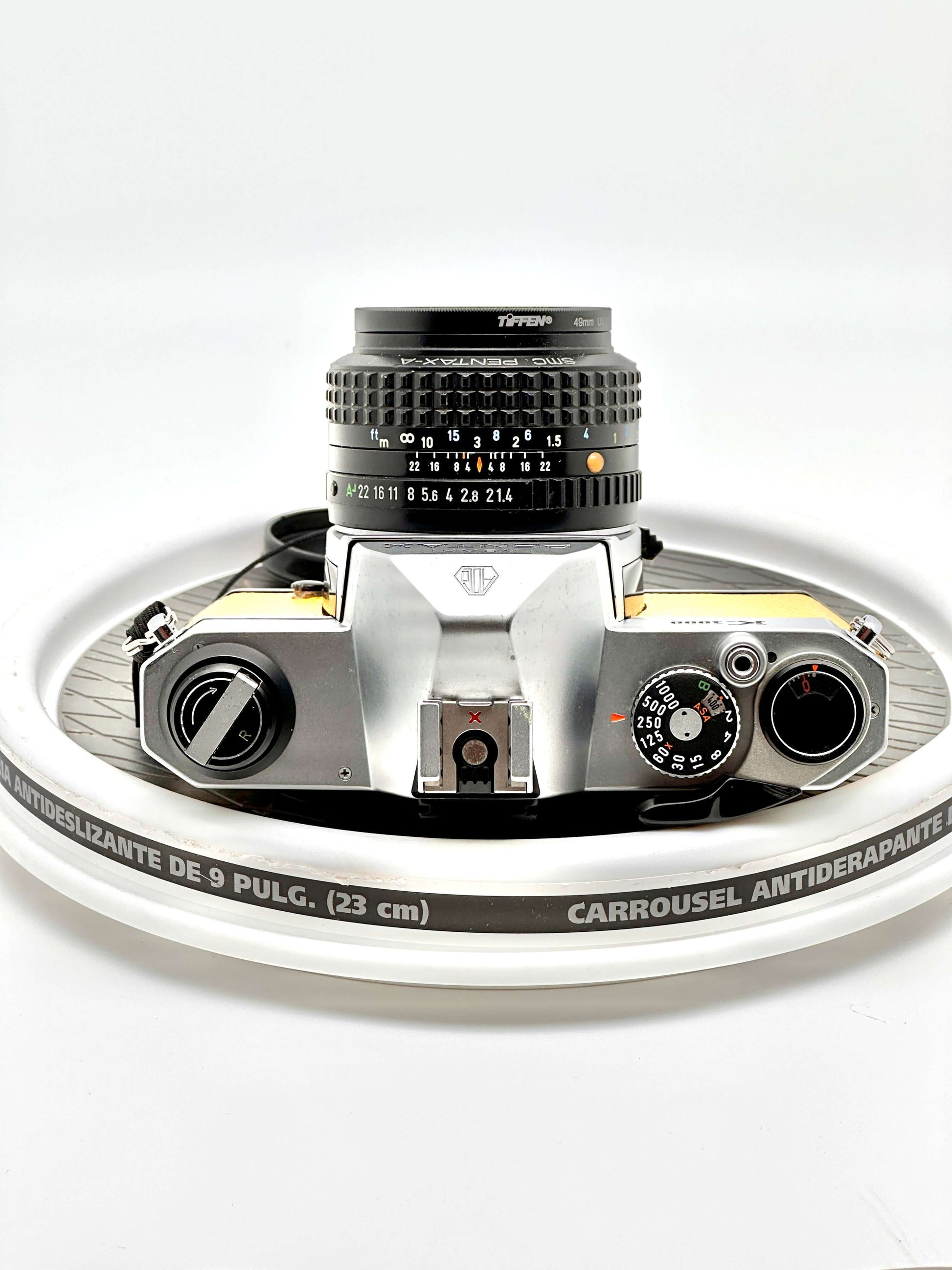 Japanese Asahi Pentax K1000 yellow 35mm film camera on a rotating display, featuring 50mm f1.4 lens.