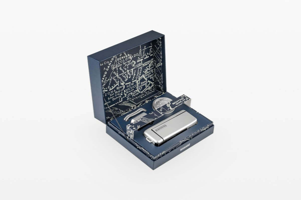 Luxury silver gadget set in open blue box with intricate design on inner lid.