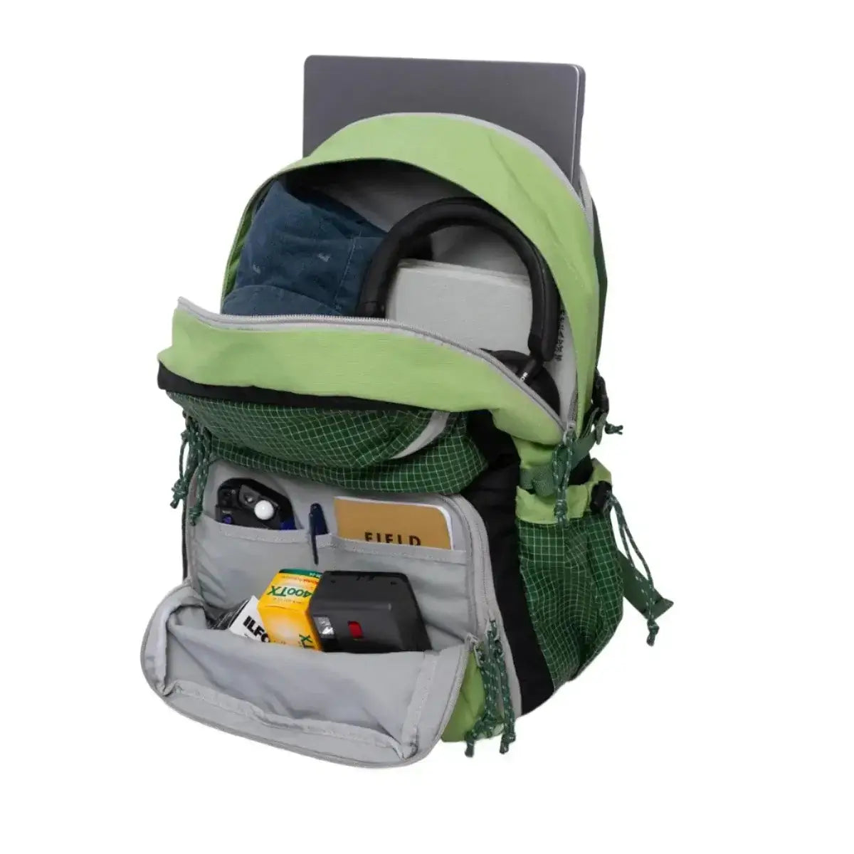 Open green backpack with multiple compartments containing a laptop, books, camera, and various items for travel or outdoor adventure.