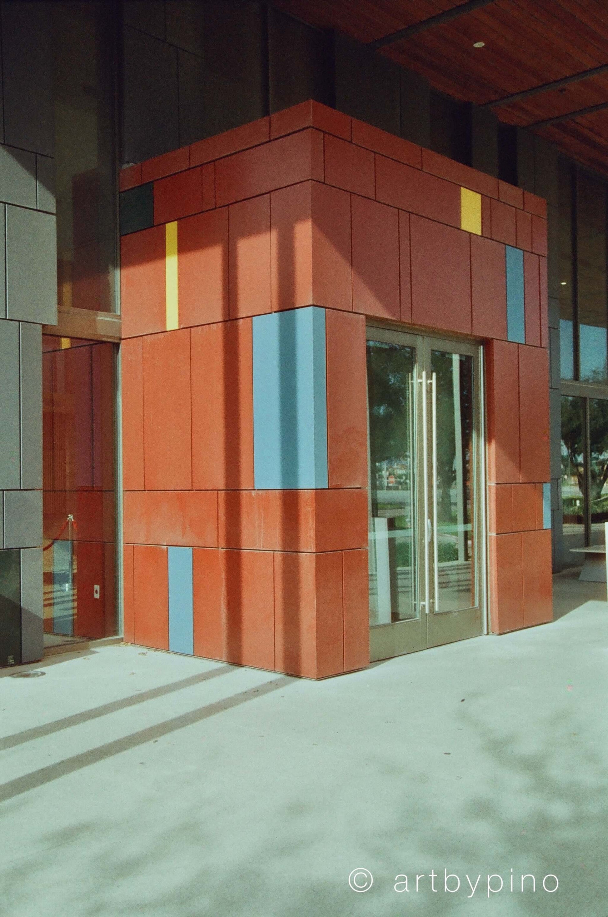 Colorful architectural entrance with red and blue panels and glass door.