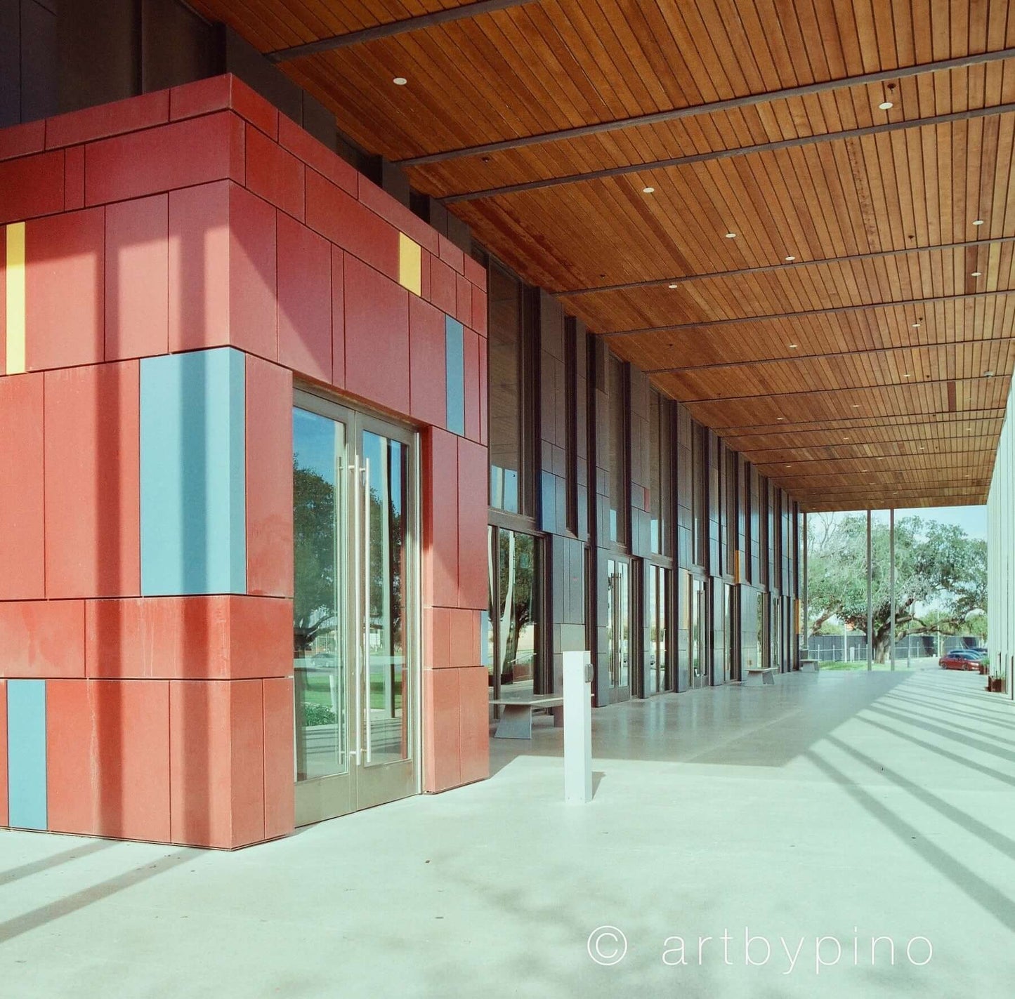 Modern architectural entrance with colorful paneling and wooden ceiling, showcasing natural light and design.