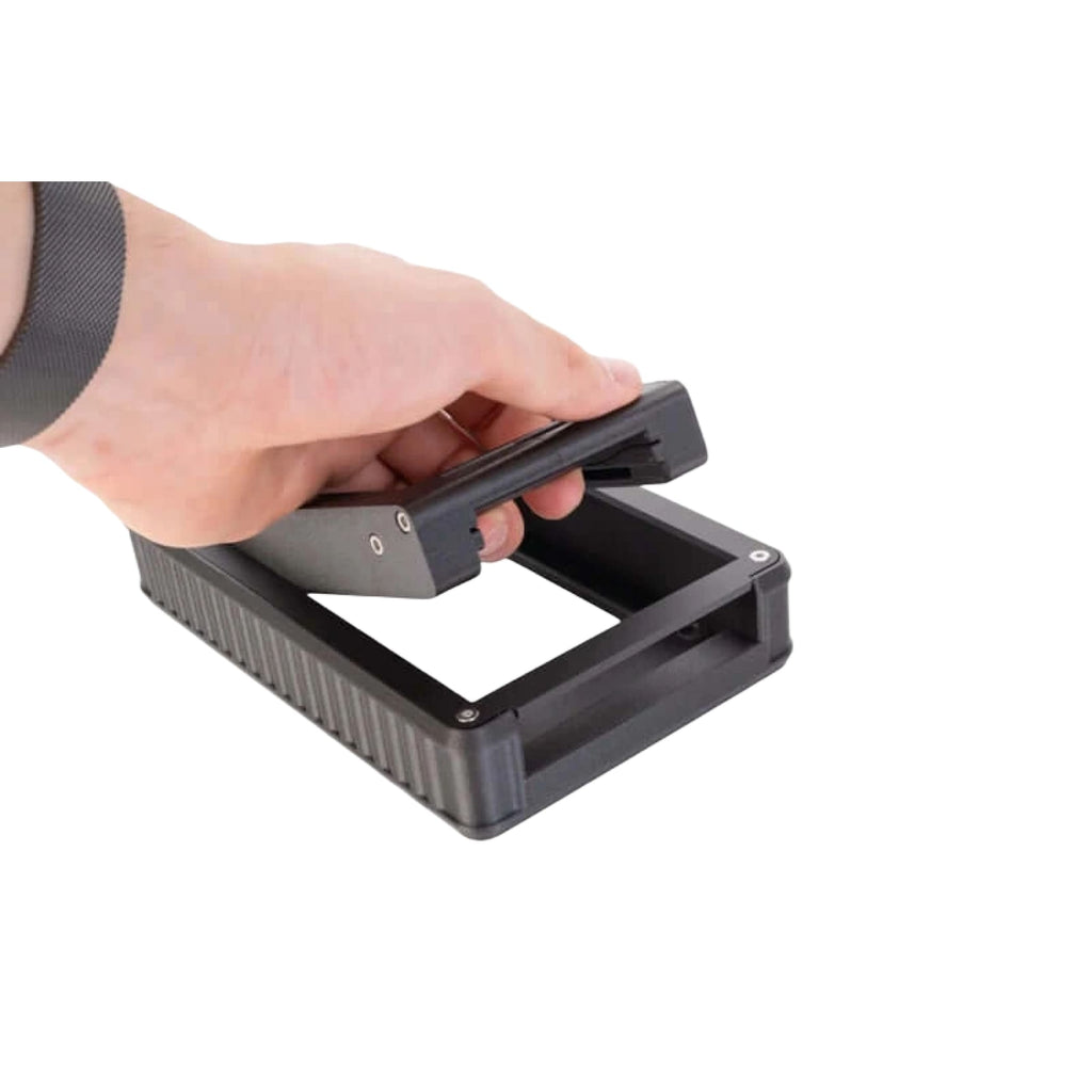 Black plastic device with textured sides and a hinged lid being held open by hand
