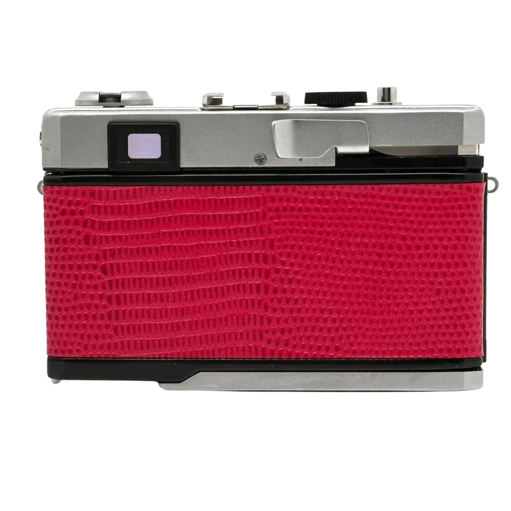 Red crocodile-textured body with silver top and black accents, classic film camera design.