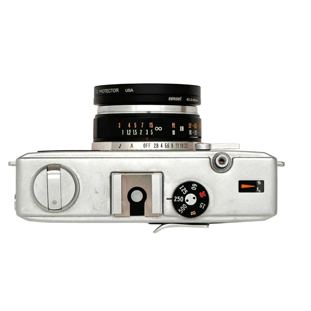 Silver-bodied rangefinder camera with a black and silver lens marked ’sensei 43-5.6mm’ mounted on top, featuring manual focus dials and shutter speed settings visible on its side panel.