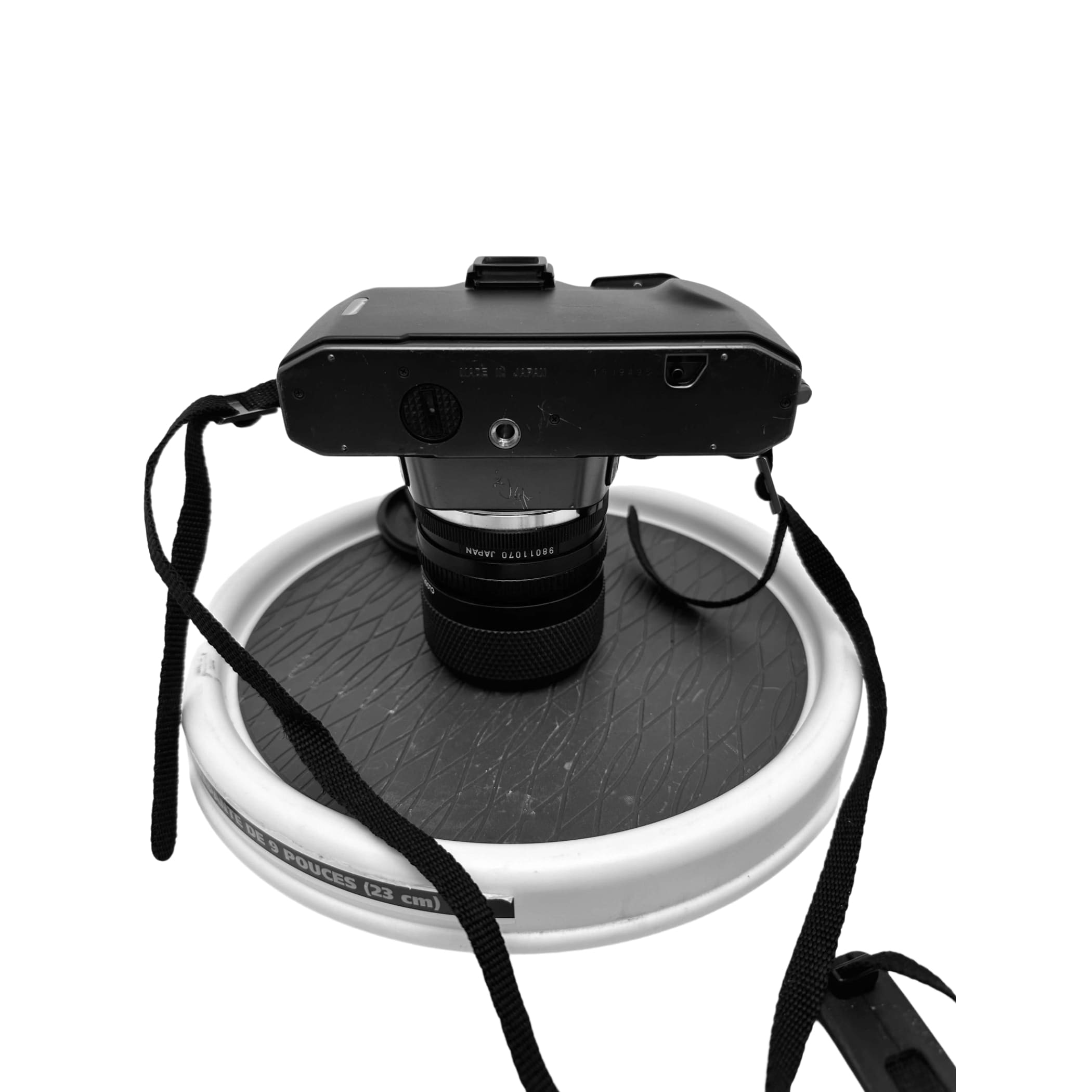 Black nikon fm2 film camera with a black lens and attached strap, resting on a circular stand.