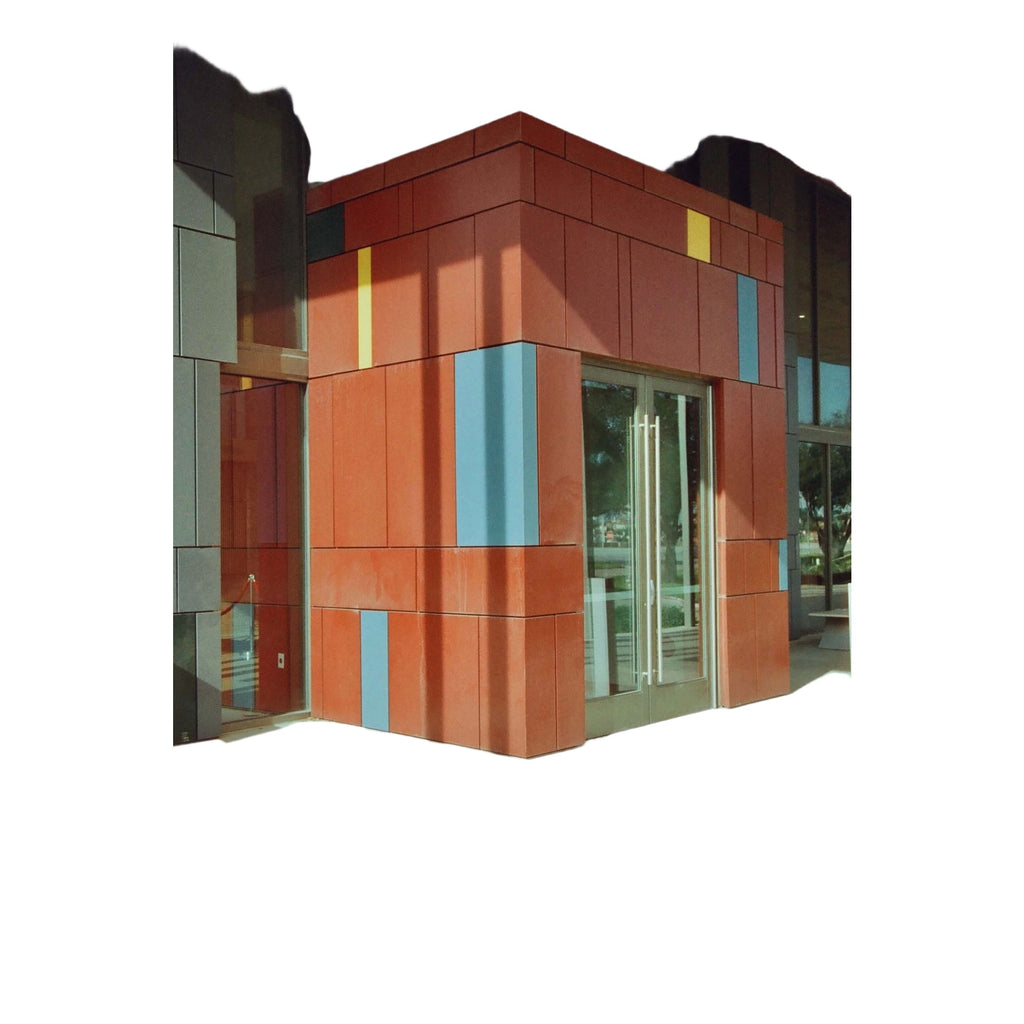 The building features a bold, geometric facade with reddish-orange panels accented by vertical stripes of yellow and blue.