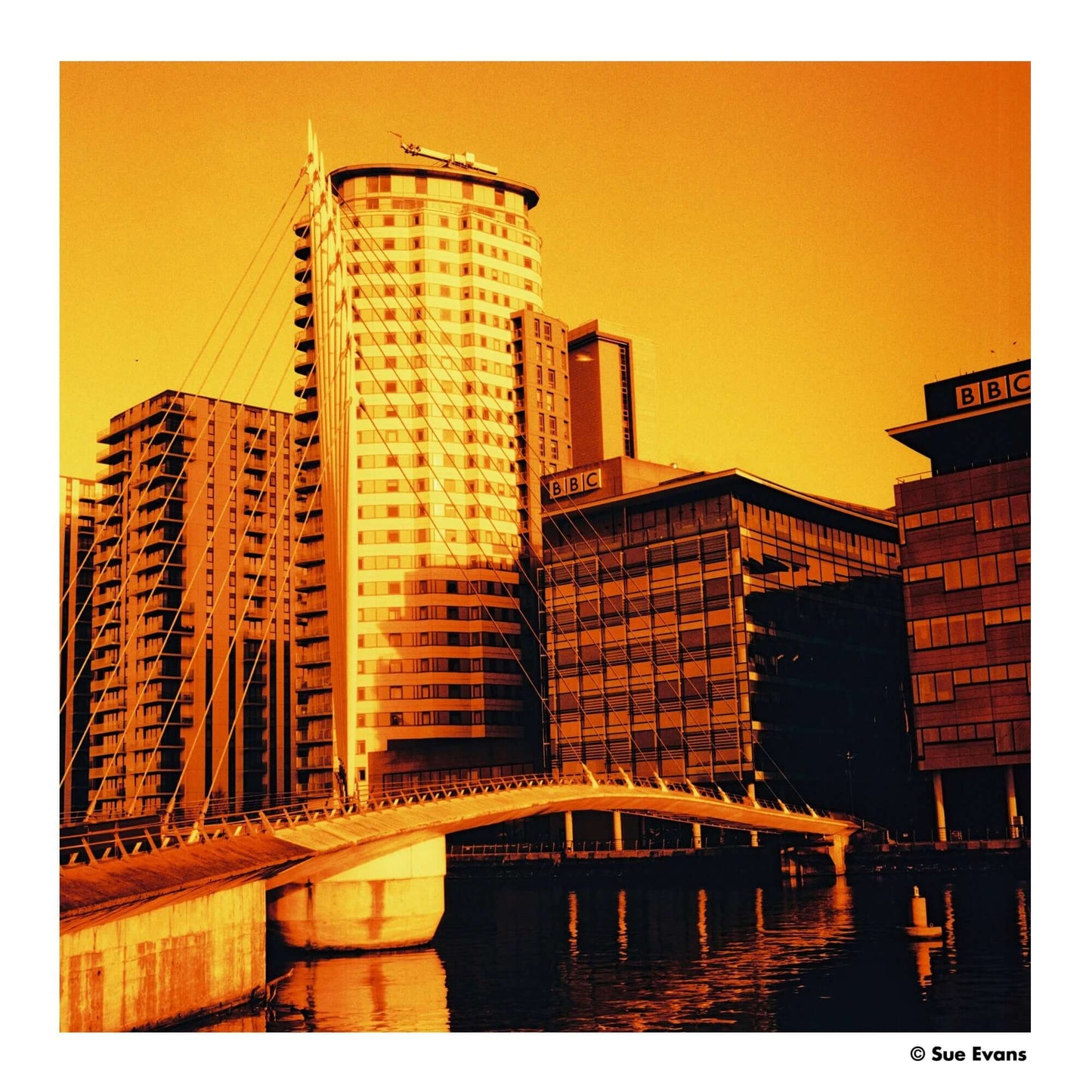 Urban landscape featuring modern buildings and a bridge under orange hues, capturing a surreal atmosphere.
