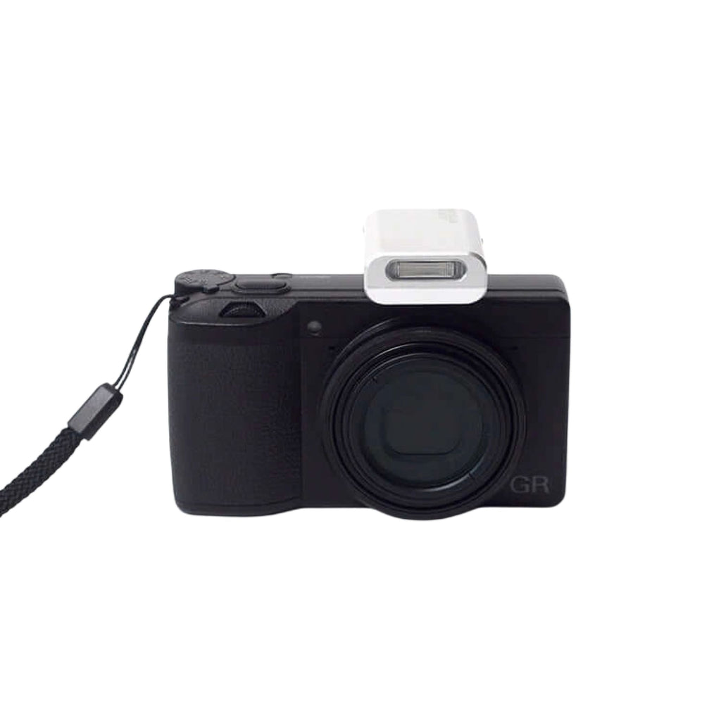 Black compact camera with a white flash attachment and black wrist strap.