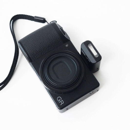 Compact digital camera with Mini Flash V2 attached, designed for on-the-go photography.