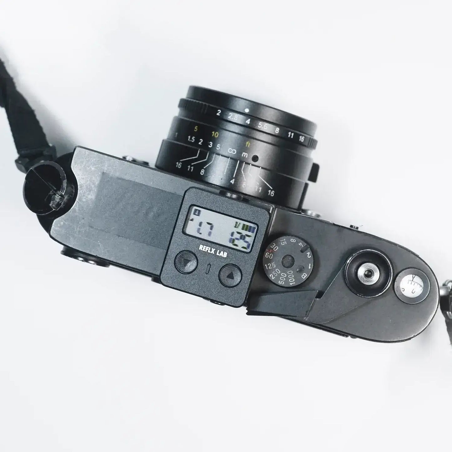 Top view of a black digital camera with an LCD screen and lens attached, displaying various settings on a clean white background.