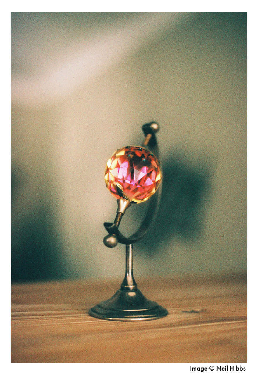 Vintage crystal ball on ornate stand with a blurred background.