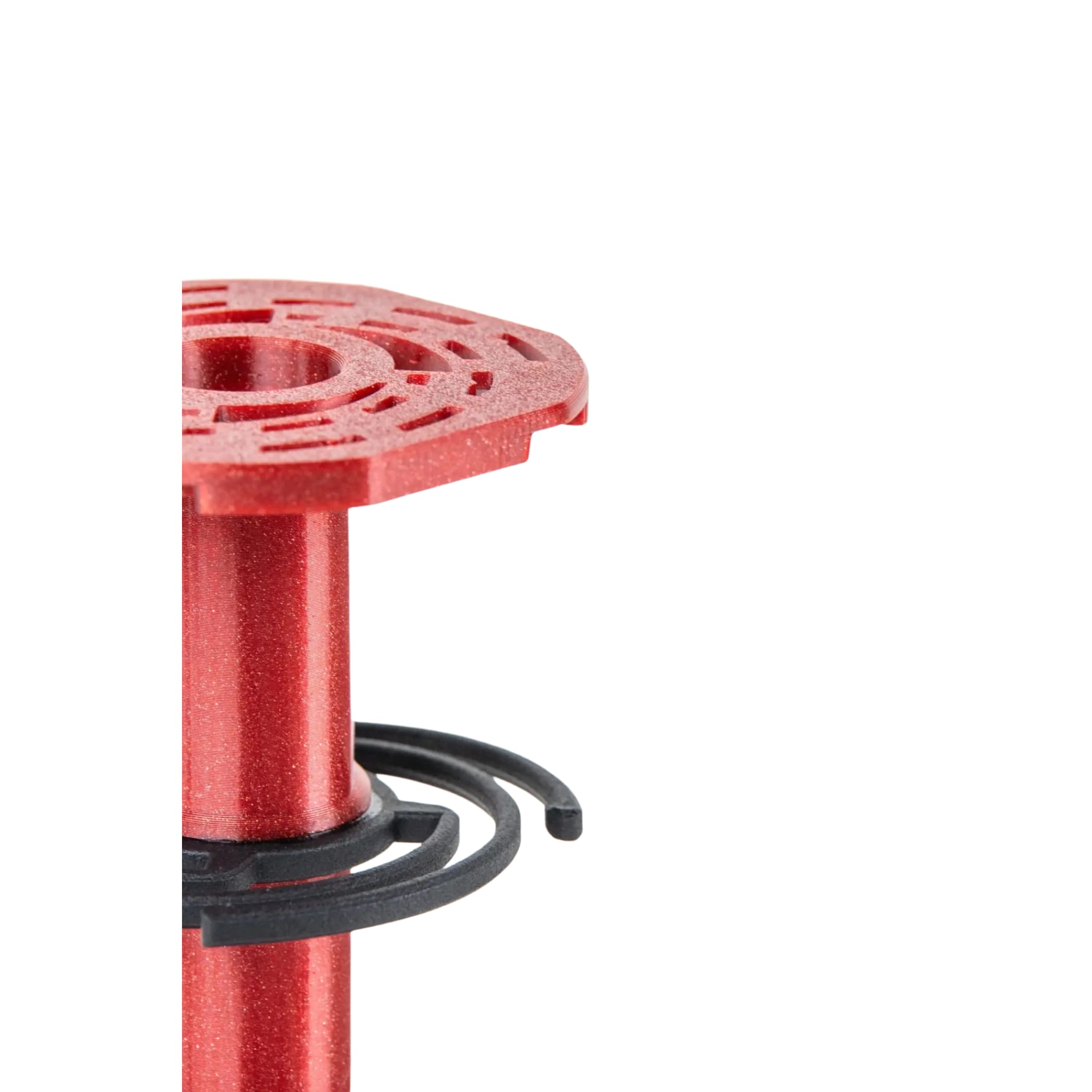Red metallic spool with intricate cut-out pattern on top and black plastic rings wrapped around its base.