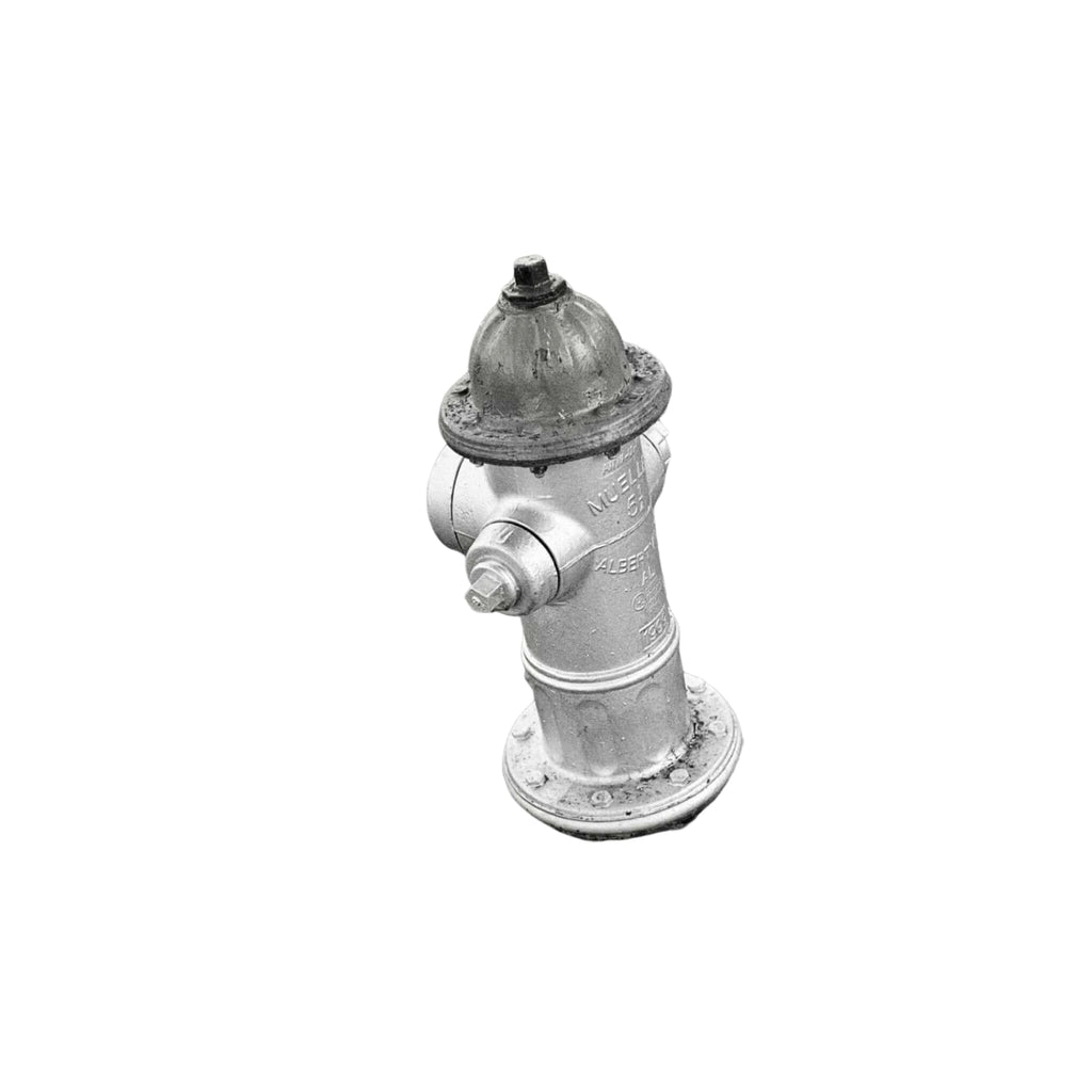 A classic silver fire hydrant with a domed top and bolted caps, standing on a bed of gravel.