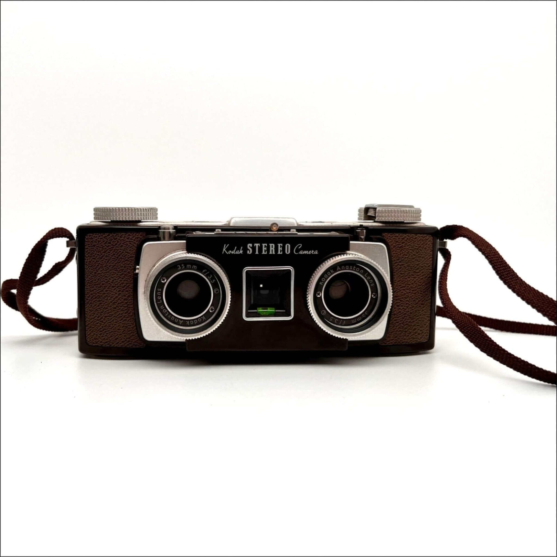 Vintage Kodak Stereo camera with dual lenses and brown case on a white background.