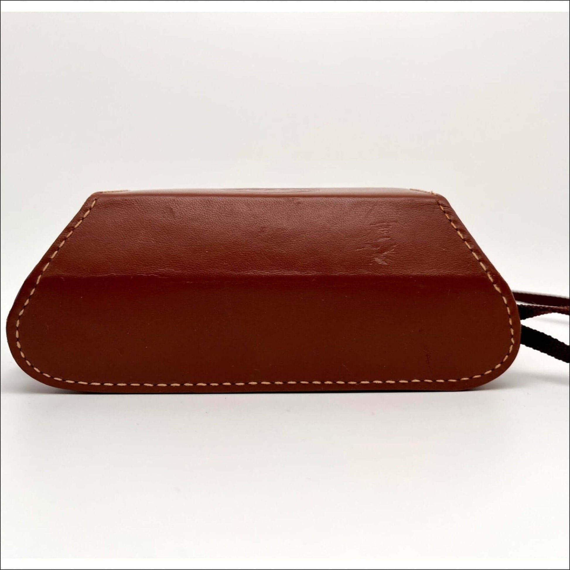 Brown leather handbag with white stitching and a strap in a minimalist design on a white background