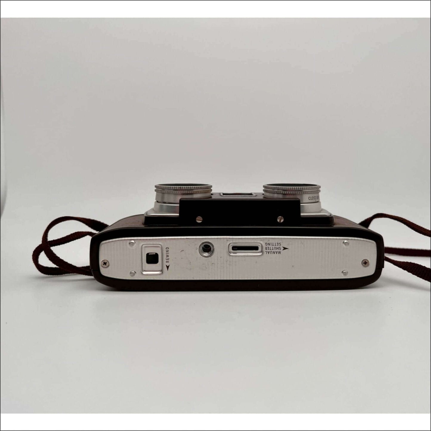 Bottom view of a vintage camera showing the battery compartment, tripod mount, and connection ports against a white background.