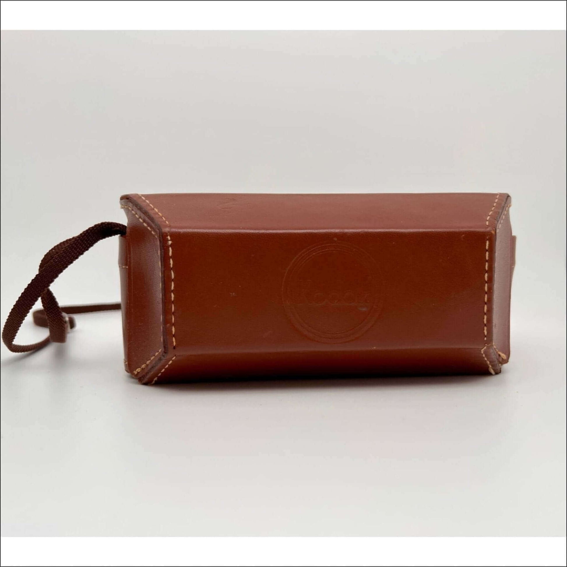 Brown leather rectangular case with white stitching and a looped strap on one side