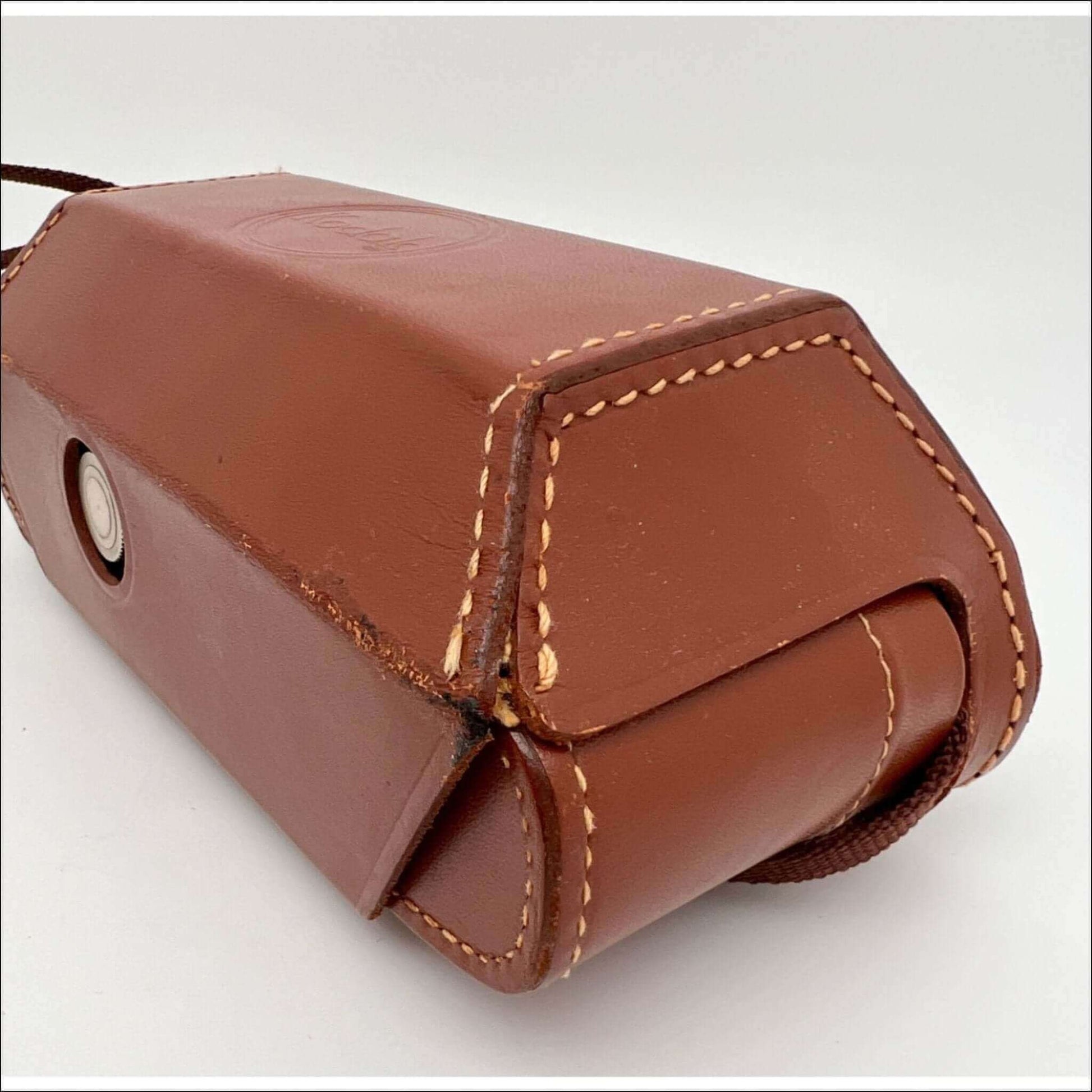 Close-up of a brown leather camera case with visible stitching and button closure.